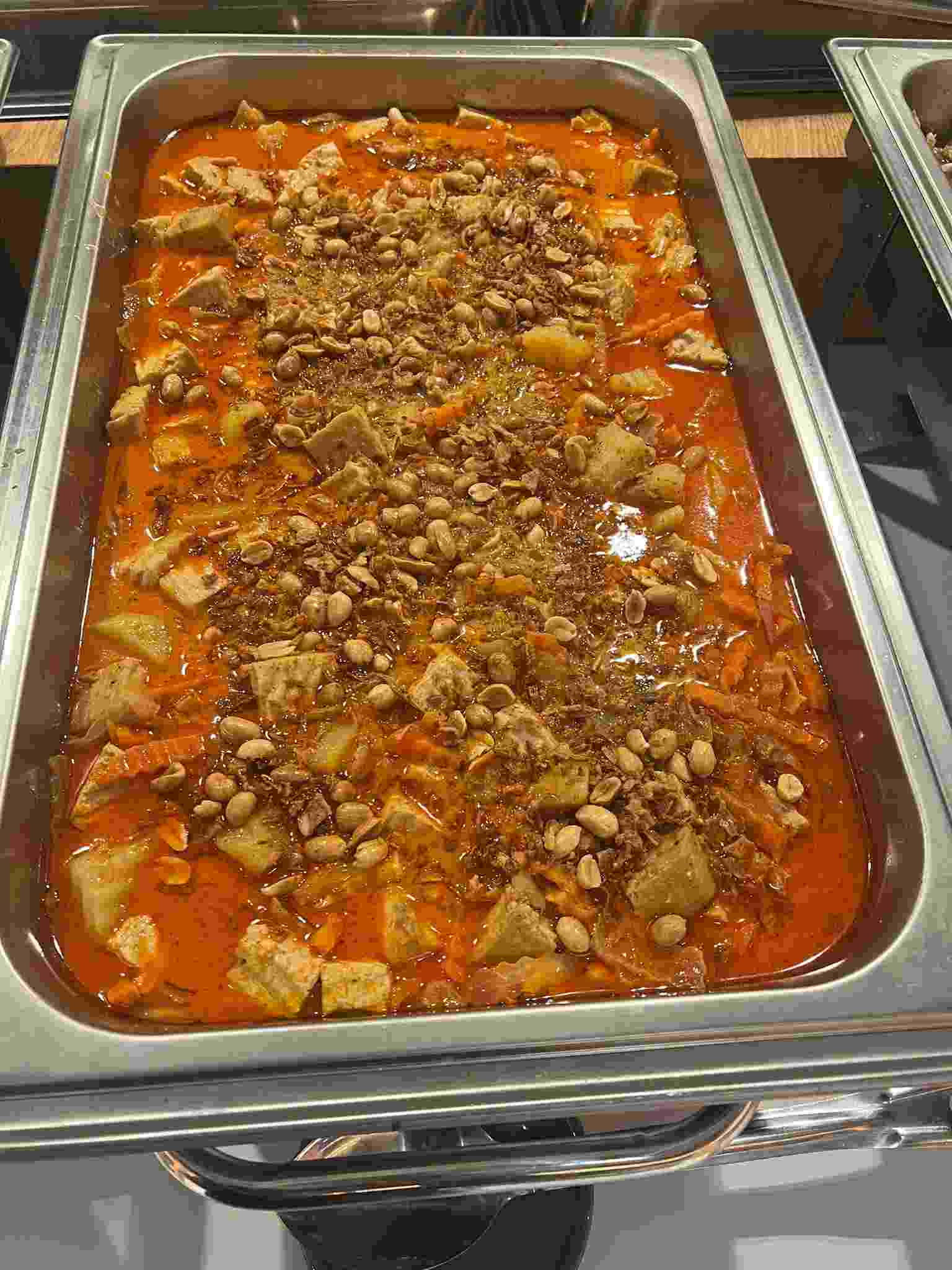 Massaman curry with potatoes and peanuts served in a catering chafing dish